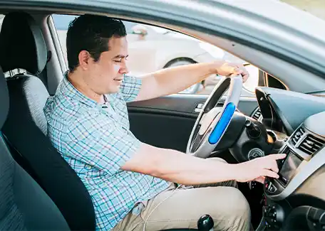 Man adjusting car radio while driving